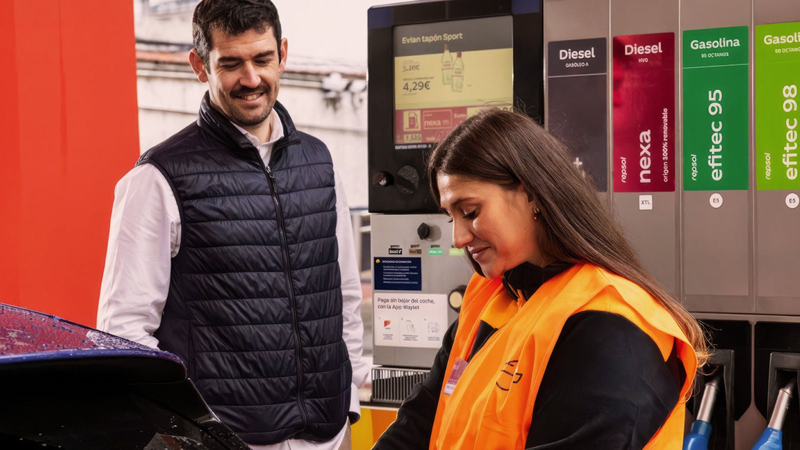 Repsol employee assisting a customer at a fuel pump.