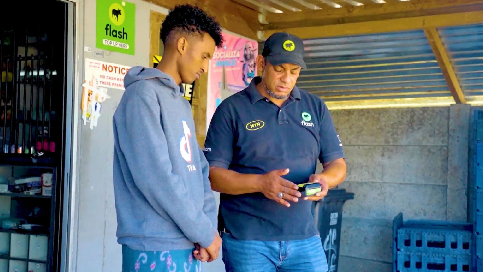 A man in a blue suit smiling with his arms crossed in front of a housing complex.