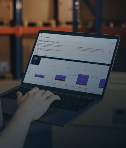 Person using a laptop displaying an Anaplan sizing plan in a warehouse.