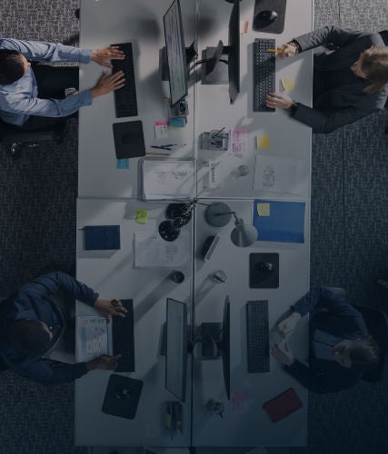 Overhead view of professionals working at desks with computers in an office.