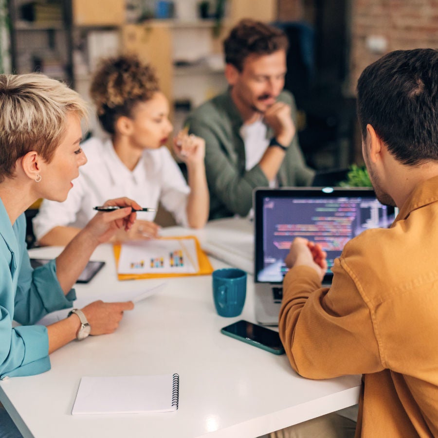 Several people seated at a table, focused on their laptops, fostering teamwork and collaboration in a modern workspace.