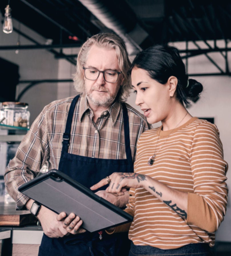 Man and woman in a shop looking at a tablet together. 