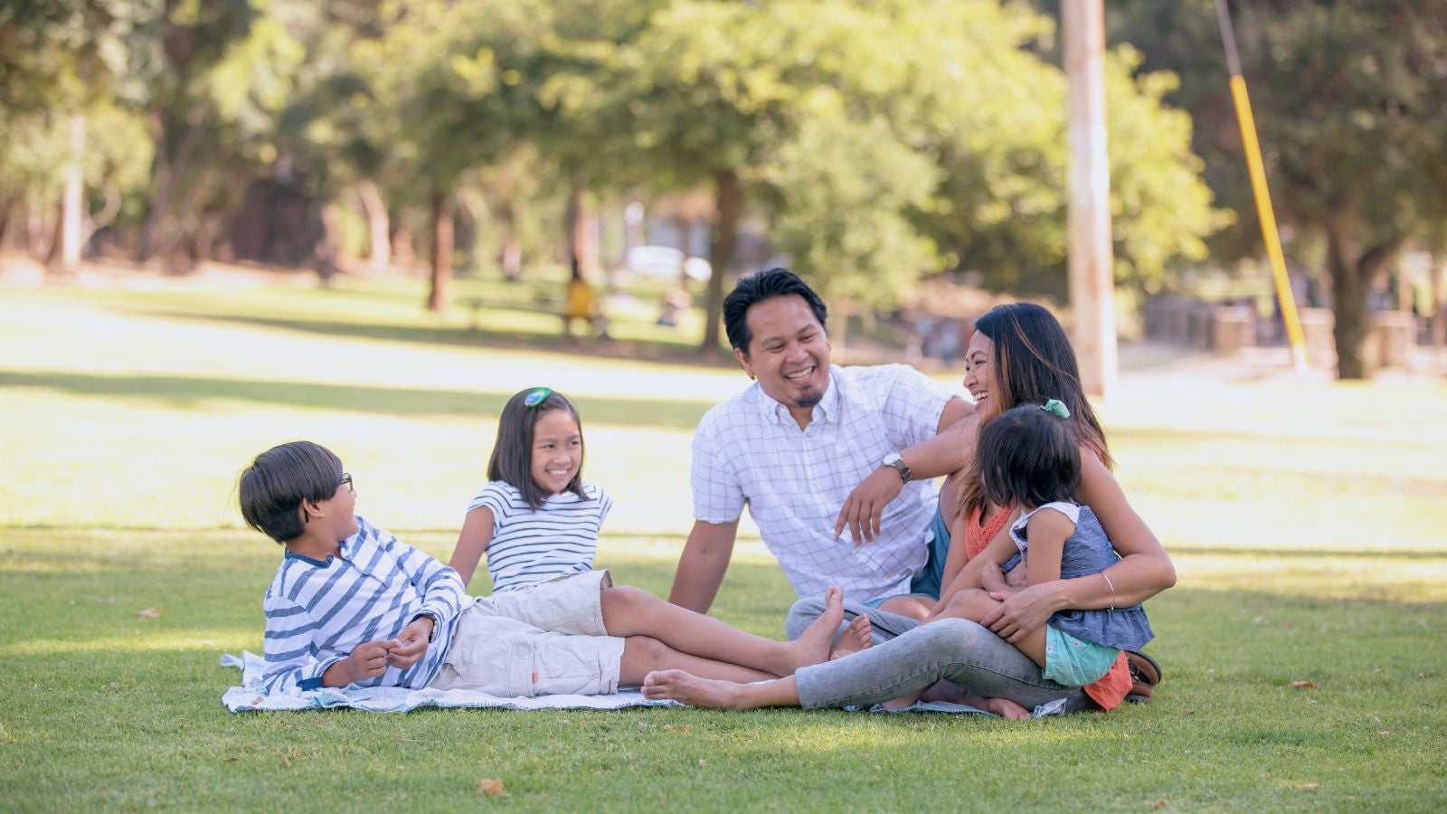 Family smiling and sitting in a park