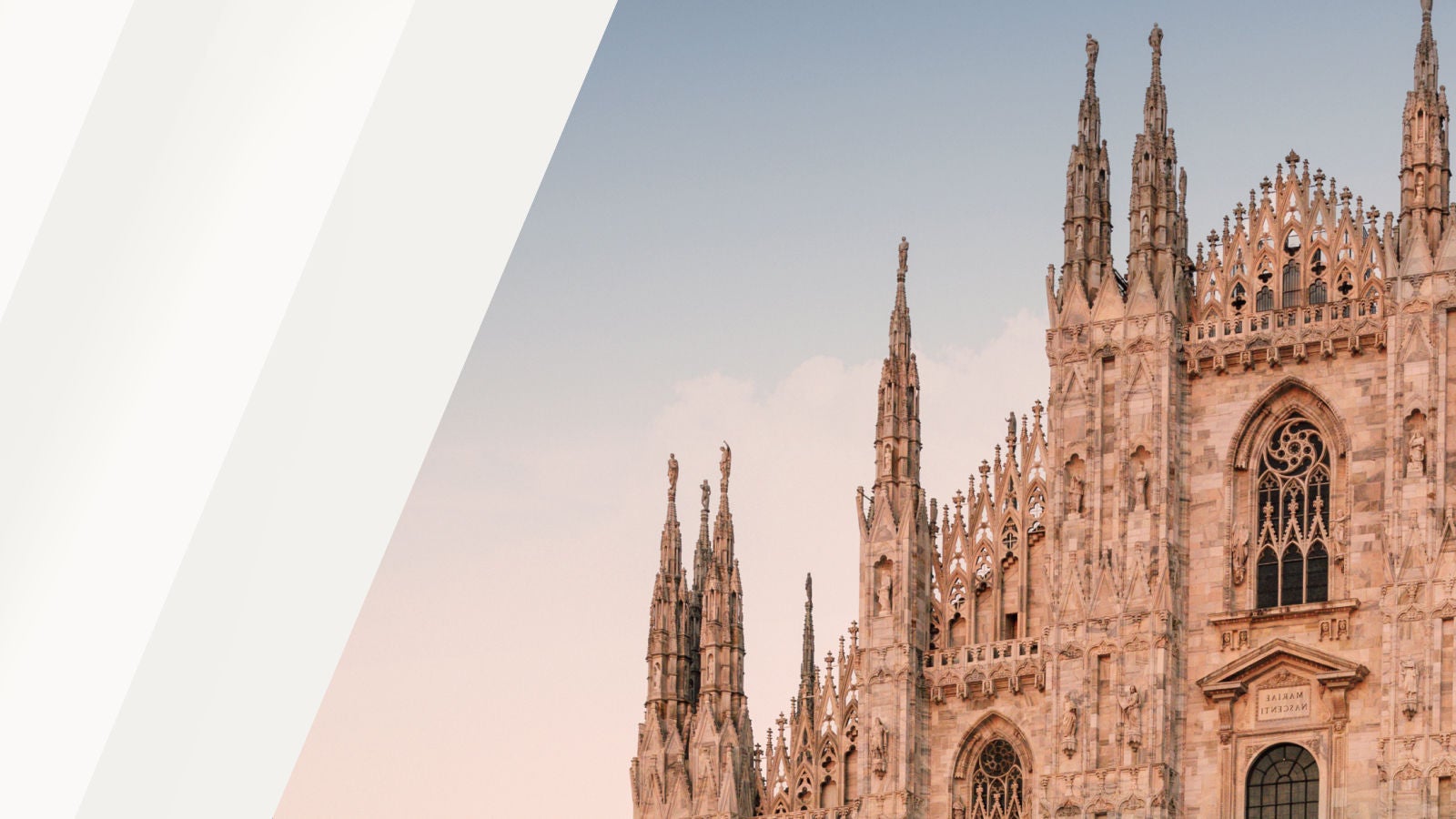 The Duomo di Milano cathedral with its ornate Gothic spires against a pale sky in Milan, Italy.