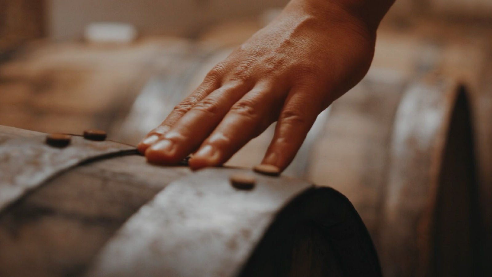Close up image of a hand touching a wine barrel