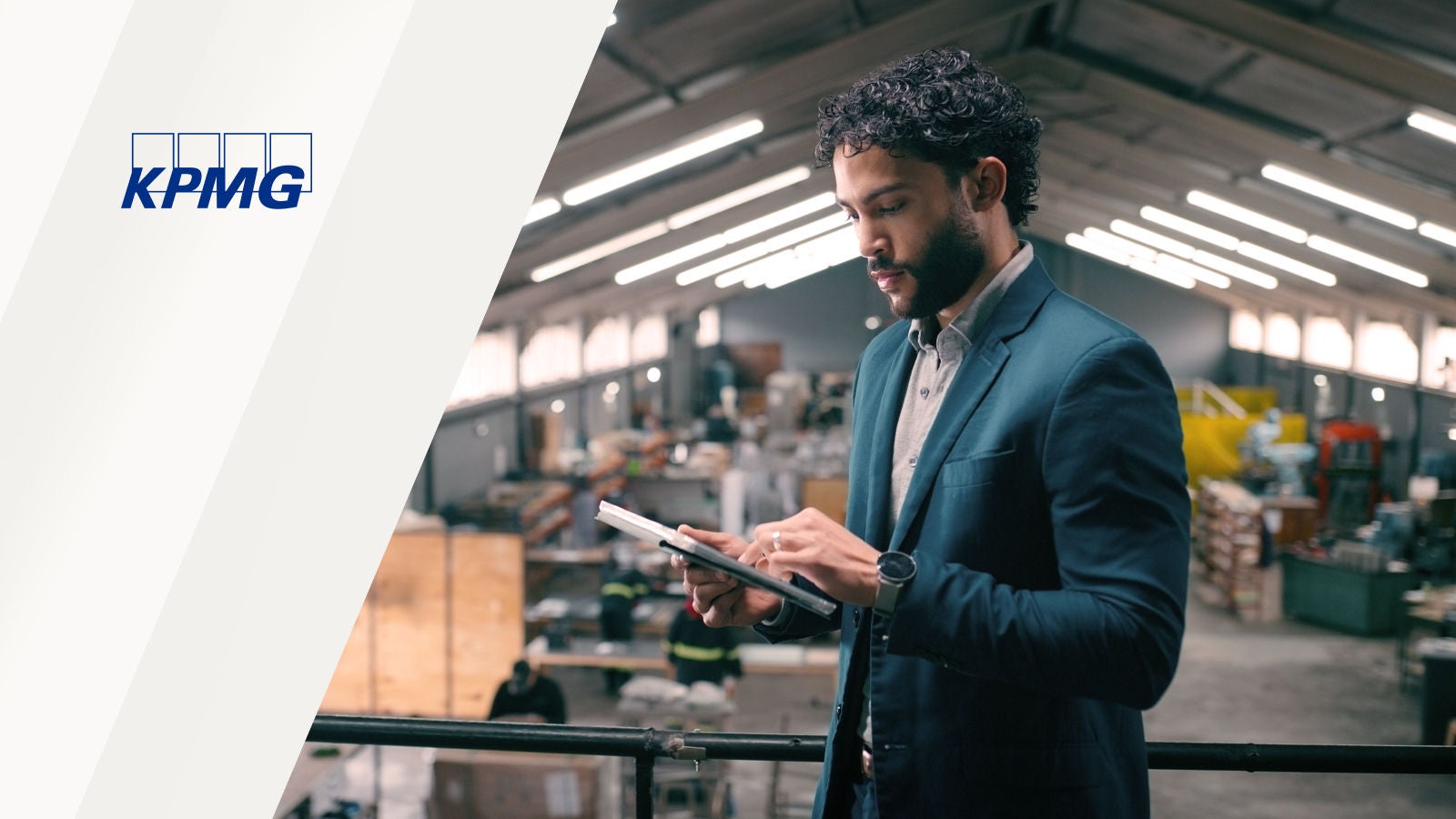 Business professional using a tablet in a warehouse, with the KPMG logo displayed.