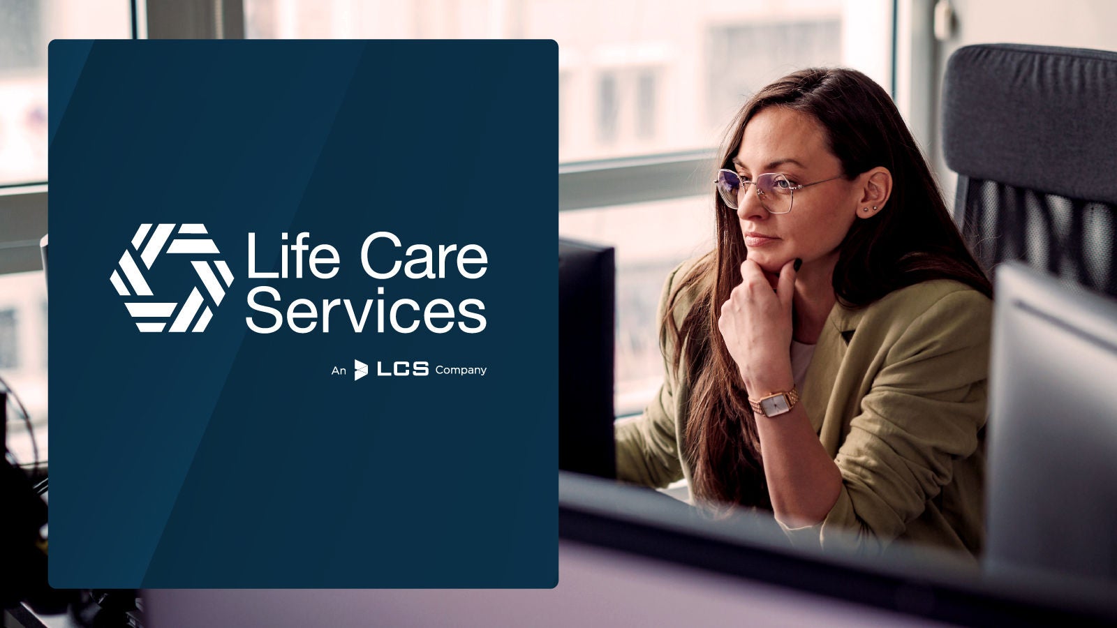 Life Care Services logo displayed on the left. A woman in glasses and a green blazer is seated at a desk in a modern office, concentrating on a computer screen.