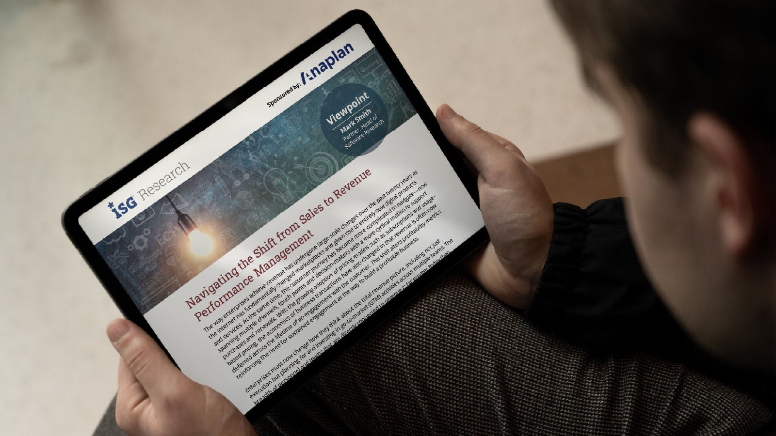 Person holding a tablet showing ISG Research Report - Navigating the shift from Sales to Revenue Performance Management