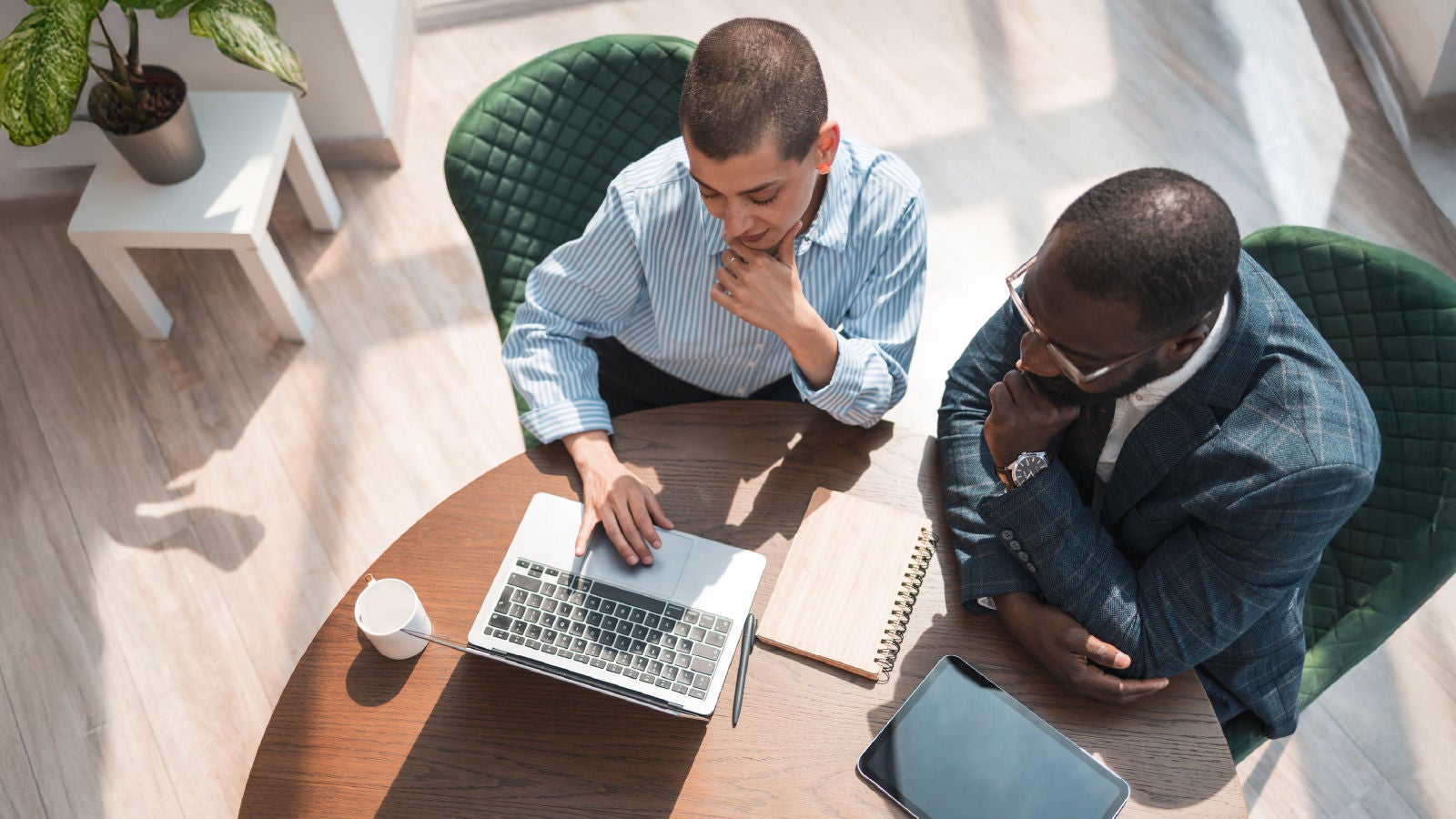 Two coworkers collaborating at a table on a laptop
