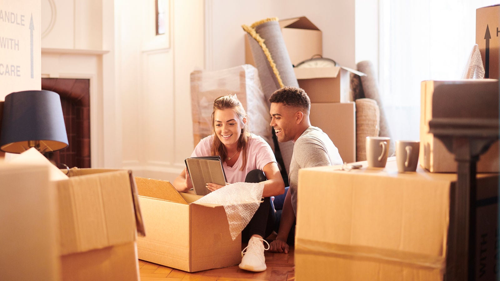 Two people unpacking boxes together in a bright room.