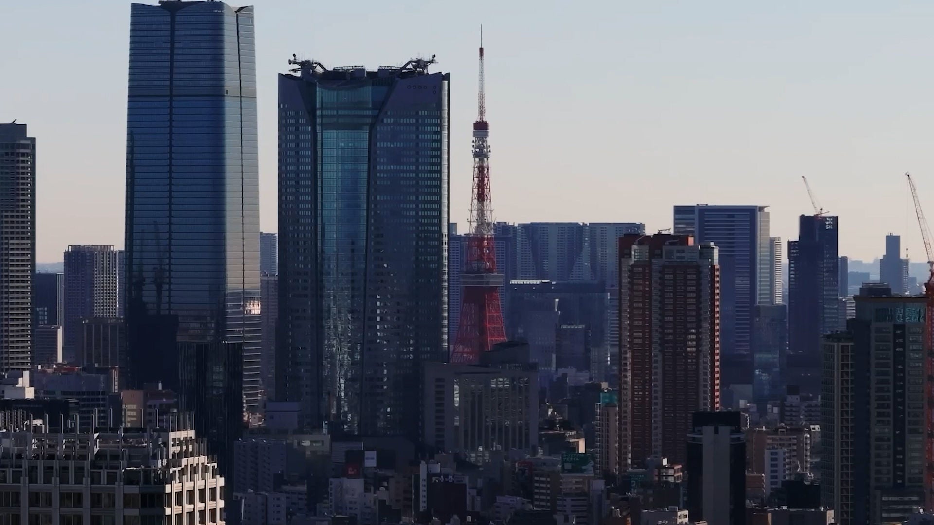 Tokyo skyline with Tokyo Tower visible among high-rise buildings.