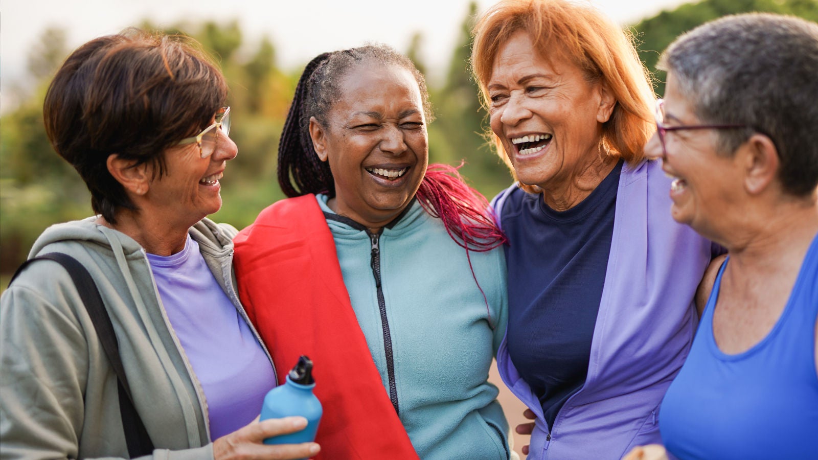 Four older women laughing together outdoors after exercising.