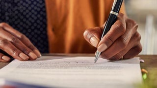 Signing a contract, using a pen to finalize an important document.