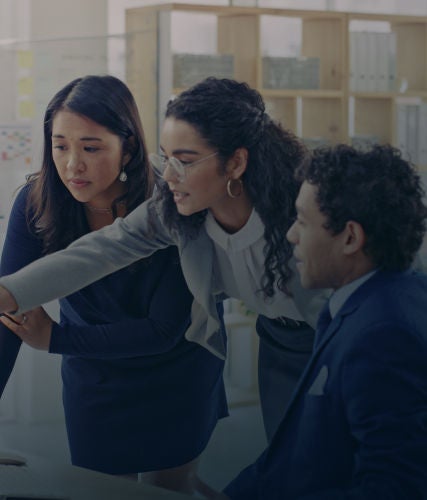 Business professionals collaborating and reviewing information on a computer screen in an office.