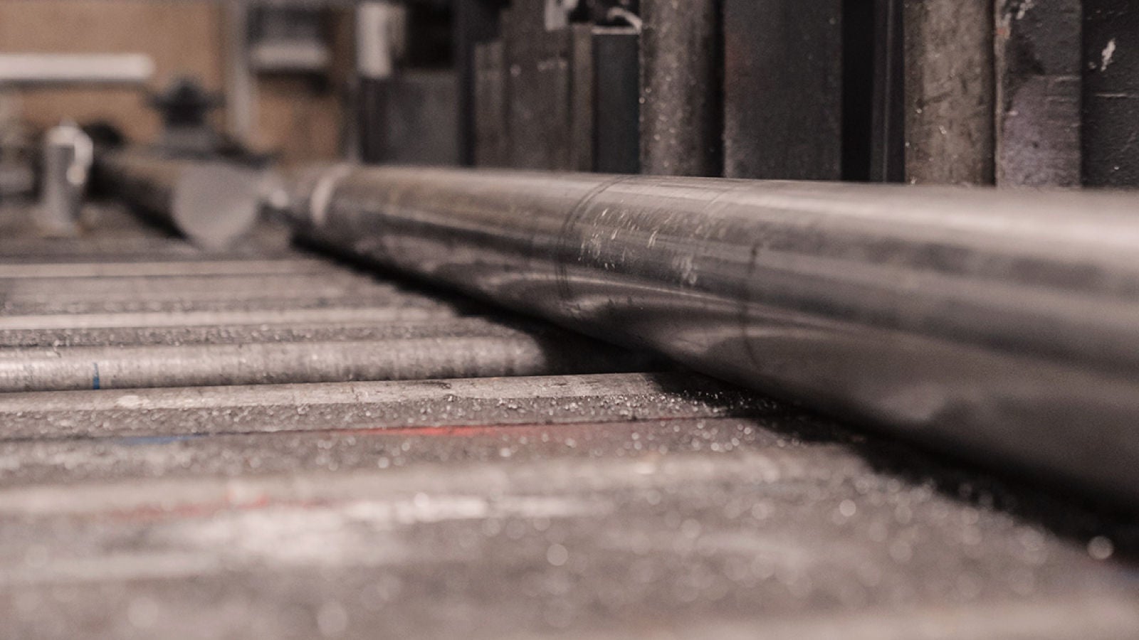 Close-up view of metal pipes on industrial rollers inside a manufacturing facility.