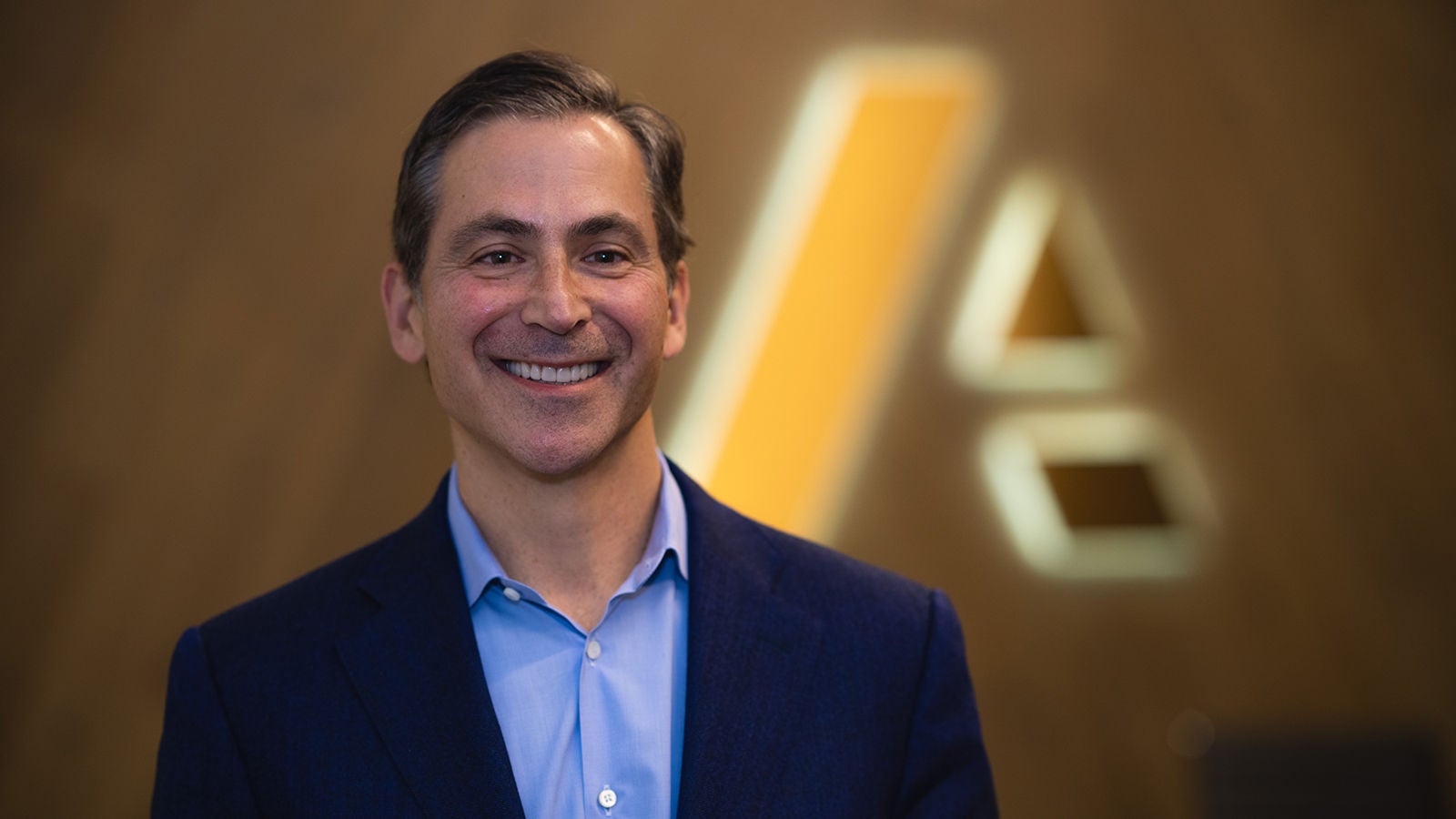 Charlie Gottdiener — businessman dressed in suit standing in front of Anaplan logo