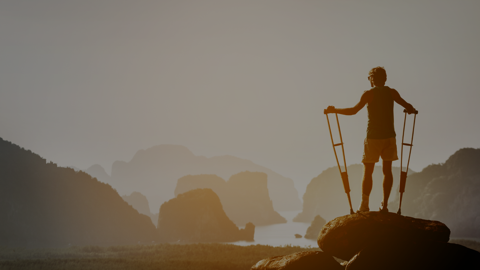 Person with crutches on the top of a mountain