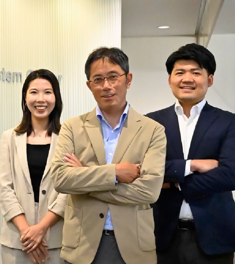 Three professionals in business attire posing confidently in a corporate office environment.