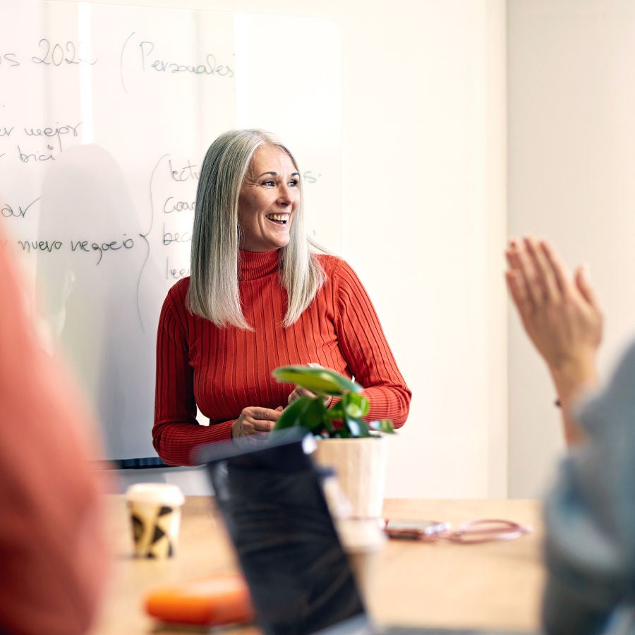 A woman presents to an audience, engaging them with her speech and visual aids in a professional setting.