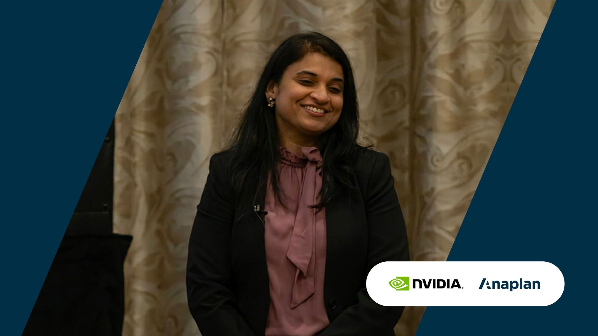 A speaker smiles during an event session in front of patterned curtains, with NVIDIA and Anaplan logos displayed.