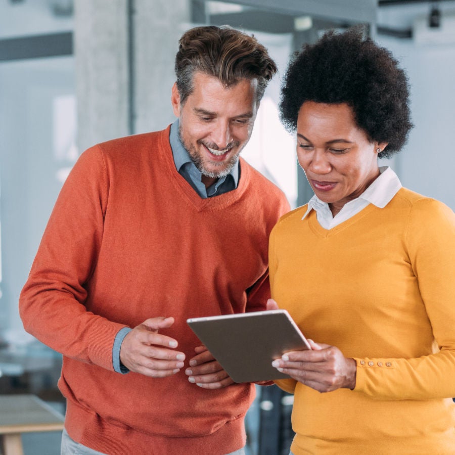 A man and woman are intently examining a tablet together, sharing insights and ideas.