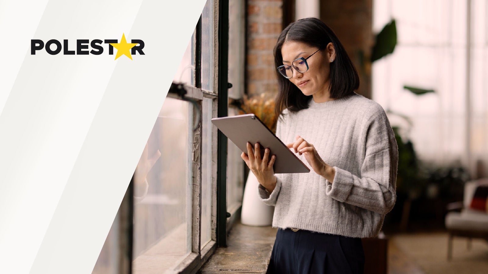 Polestar logo displayed on the left beside a woman using a tablet while standing near a window indoors.