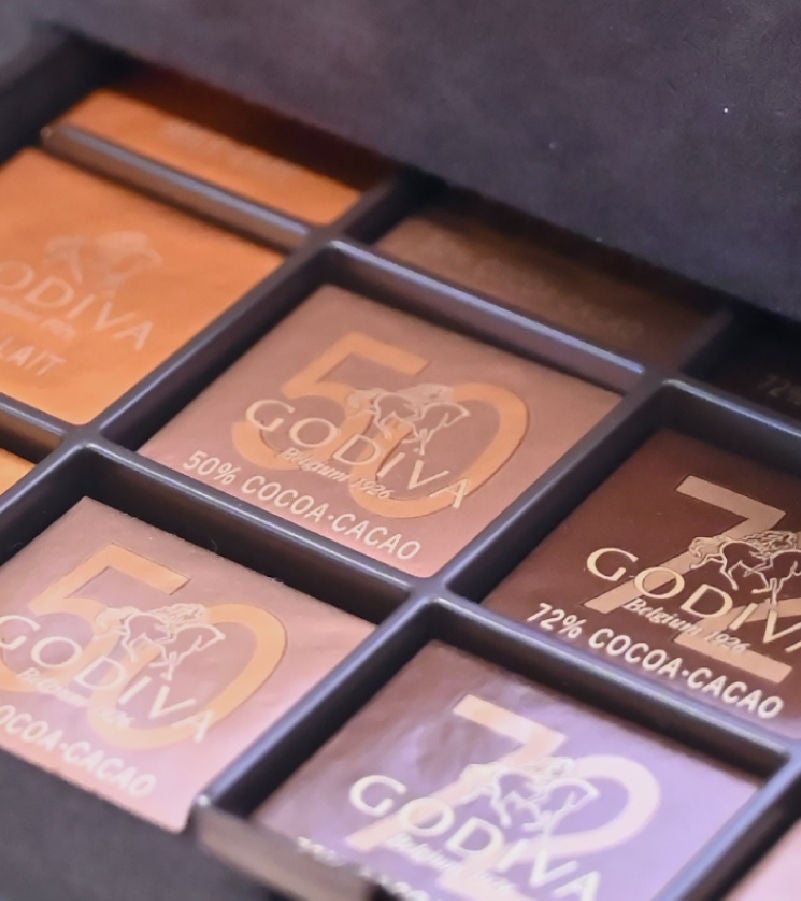 Close-up of a premium Godiva chocolate assortment in elegant packaging, showcasing different cocoa percentages.