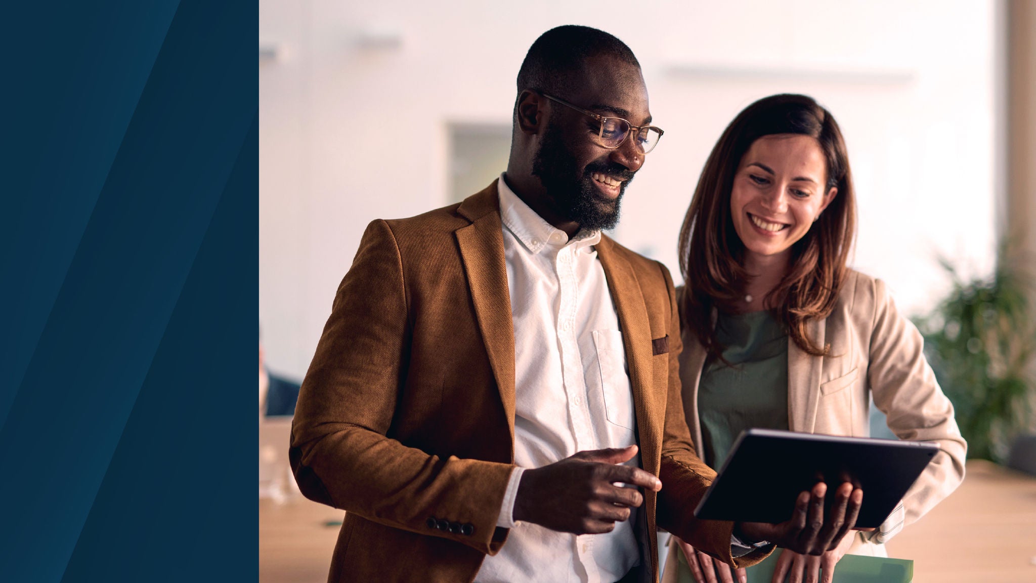 Two professionals reviewing information on a tablet together in an office setting.