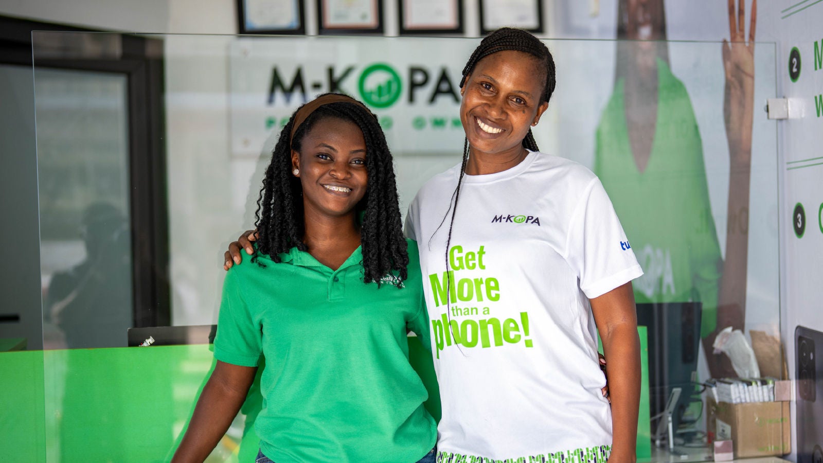 Two M-KOPA employees smiling together inside an M-KOPA retail store.