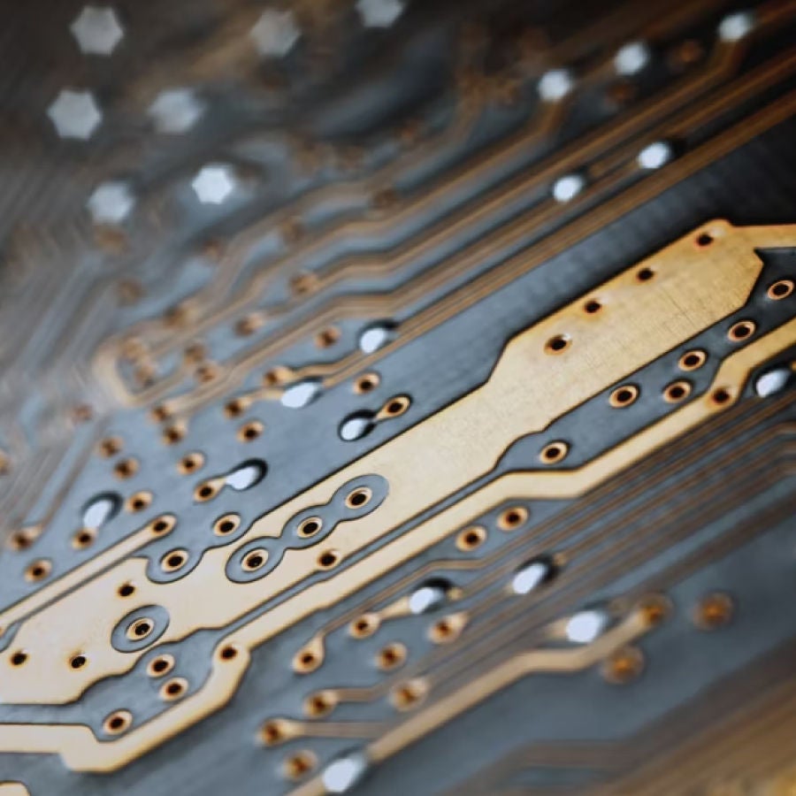Close-up view of a circuit board featuring intricate gold and black components, showcasing detailed electronic design.