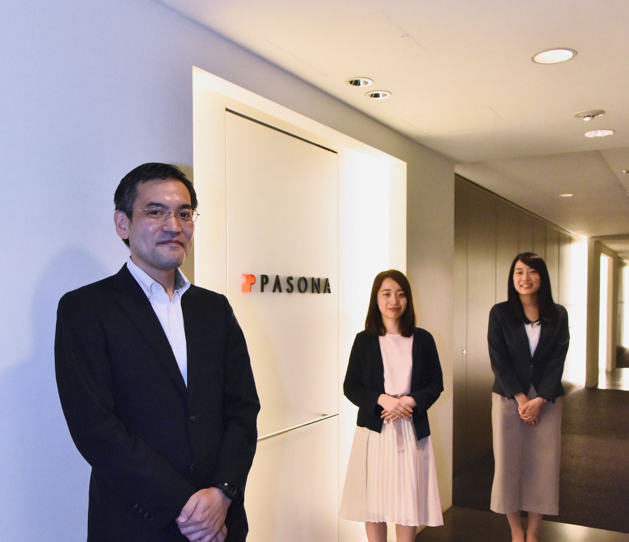 Pasona employees standing in front of their company logo