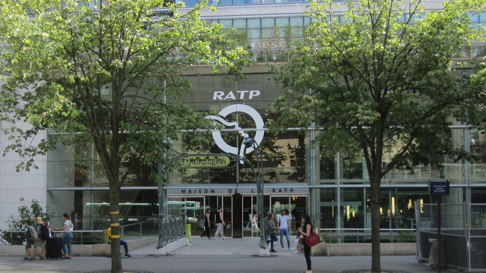 Pedestrians outside the tree-lined entrance of the RATP headquarters.