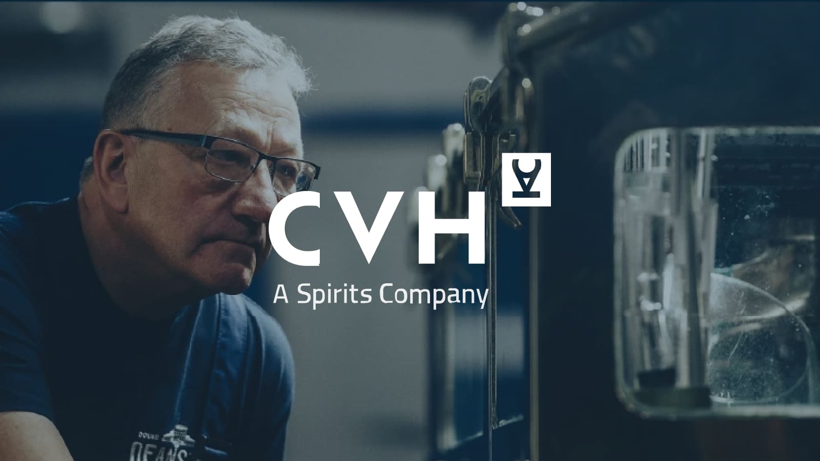 CVH Logo displayed center. A man closely examines equipment in a distillery or spirits production facility.