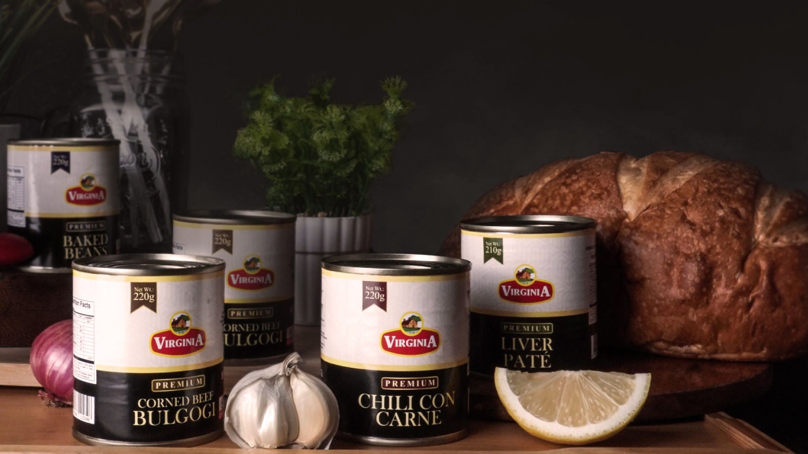 Assorted Virginia canned food products displayed with bread, garlic, onion, herbs, and a lemon wedge.