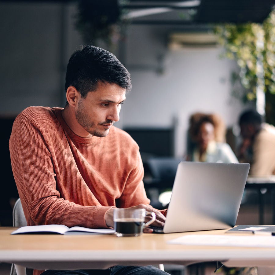 A man at a table using a laptop, concentrating on his tasks or research.