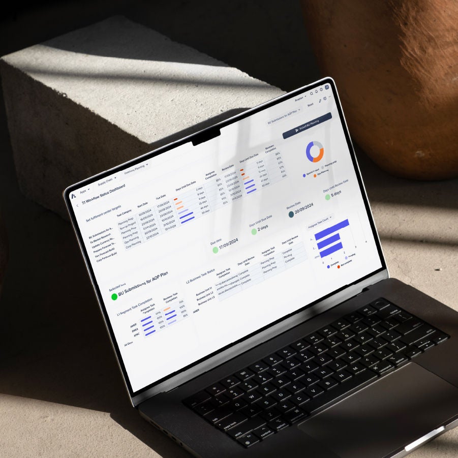 Open laptop displaying a Workflow Status Dashboard with data visualizations and charts, placed on a concrete surface with soft sunlight and shadows.