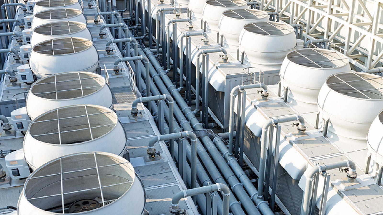 Cooling system infrastructure with industrial fans and interconnected piping arranged in parallel rows.