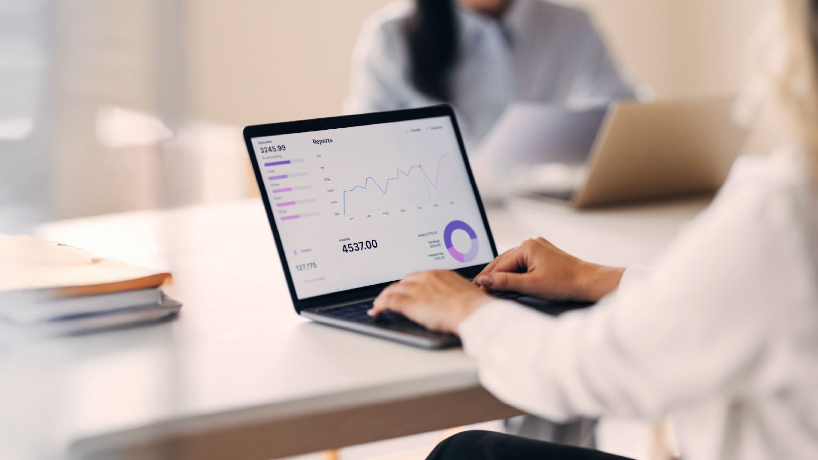 Person working on a laptop with a financial dashboard showing line and pie charts, symbolizing analysis of monthly and quarterly reporting cycles.