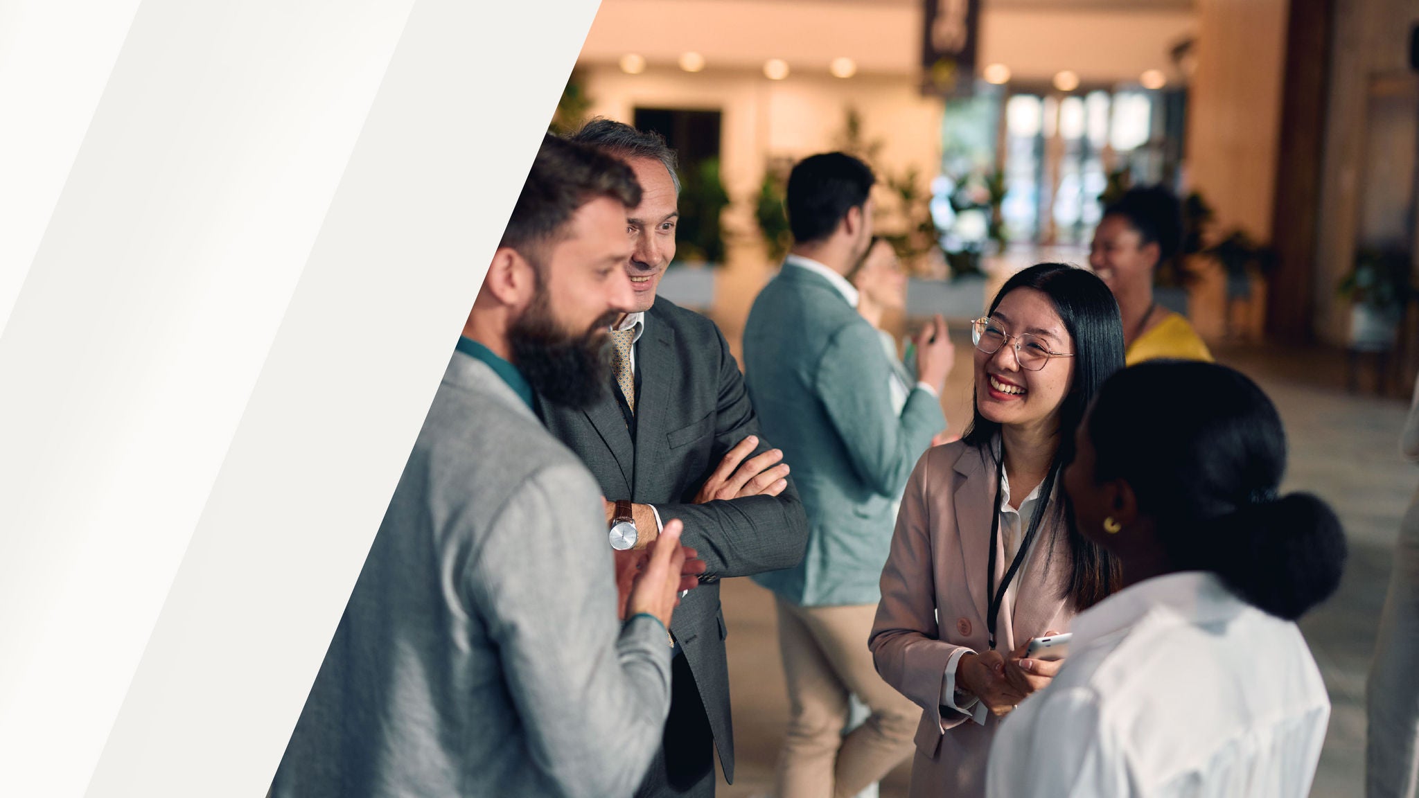 Group of professionals engaged in conversation and networking in a modern indoor event space.