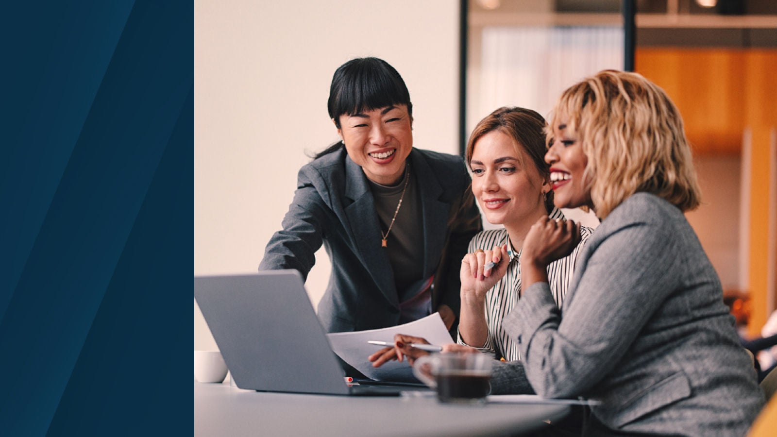 Three colleagues collaborating around a laptop in a modern office, representing teamwork and in-context communication.