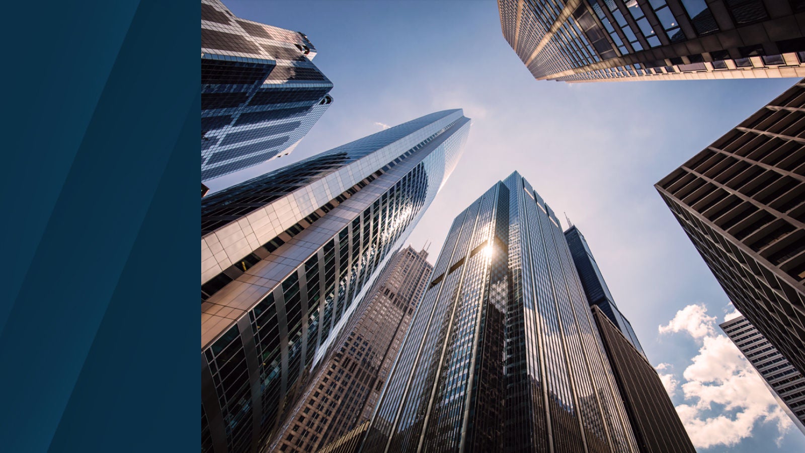 Upward view of modern skyscrapers against a blue sky with light clouds, showcasing reflective glass architecture in a business district.