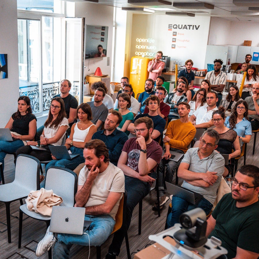 A diverse group of individuals seated in chairs, engaged in conversation within a well-lit room.