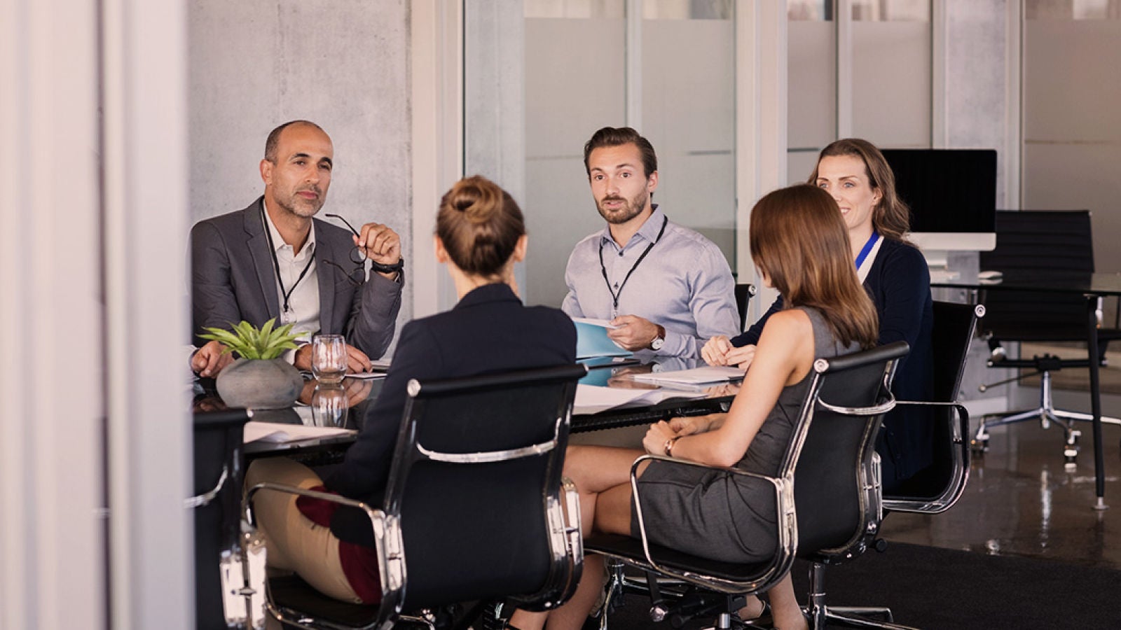 Business professionals seated around a conference table during a meeting in a modern office.