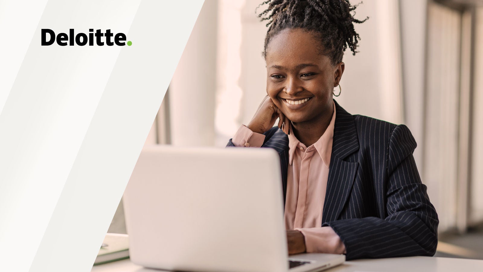 A woman in a pinstripe blazer smiles while using a laptop in a well-lit office setting. Deloitte logo appears on the left over a light background.