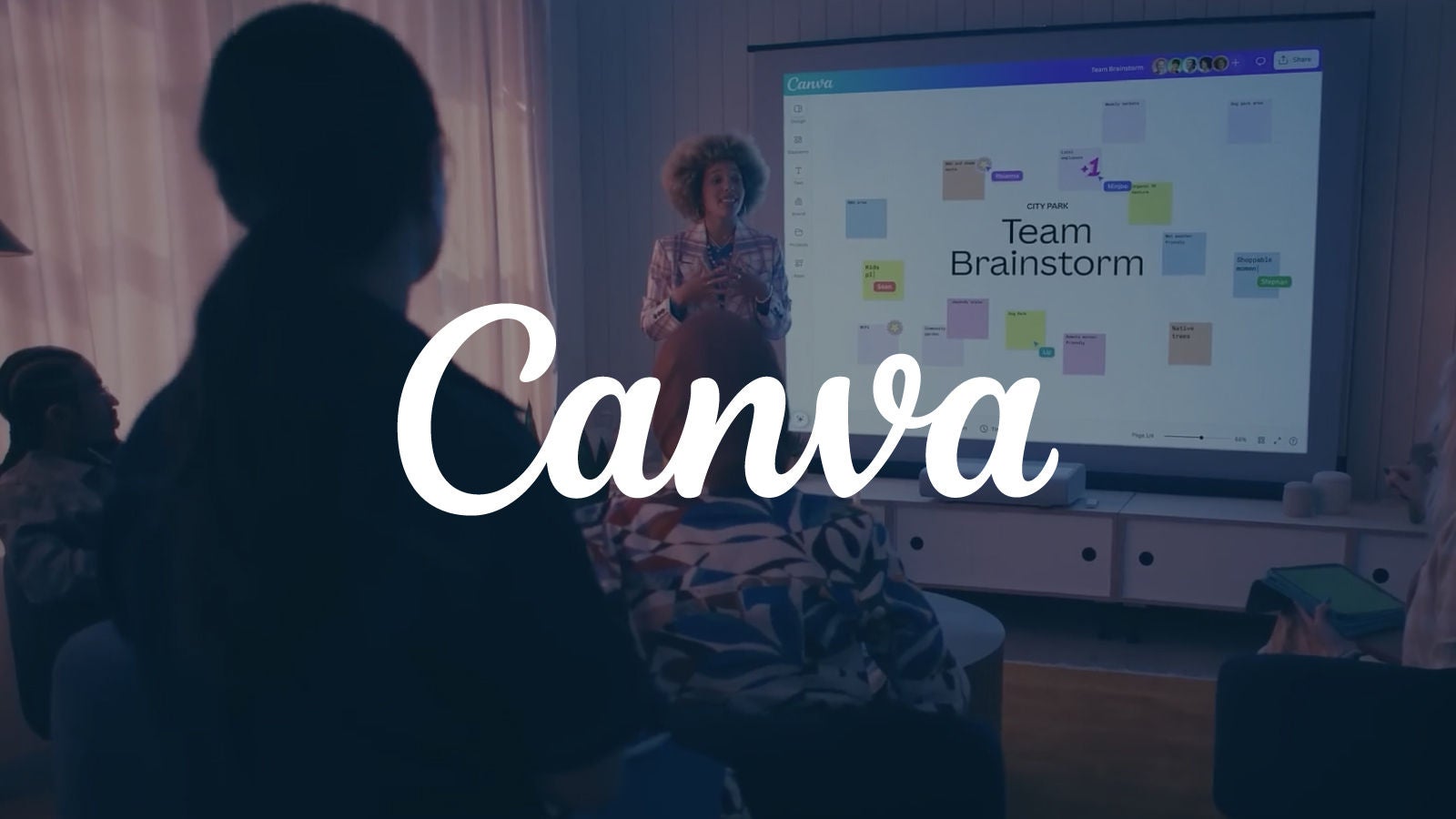 Canva logo displayed over a dimmed background of a team watching a presenter lead a brainstorm session.