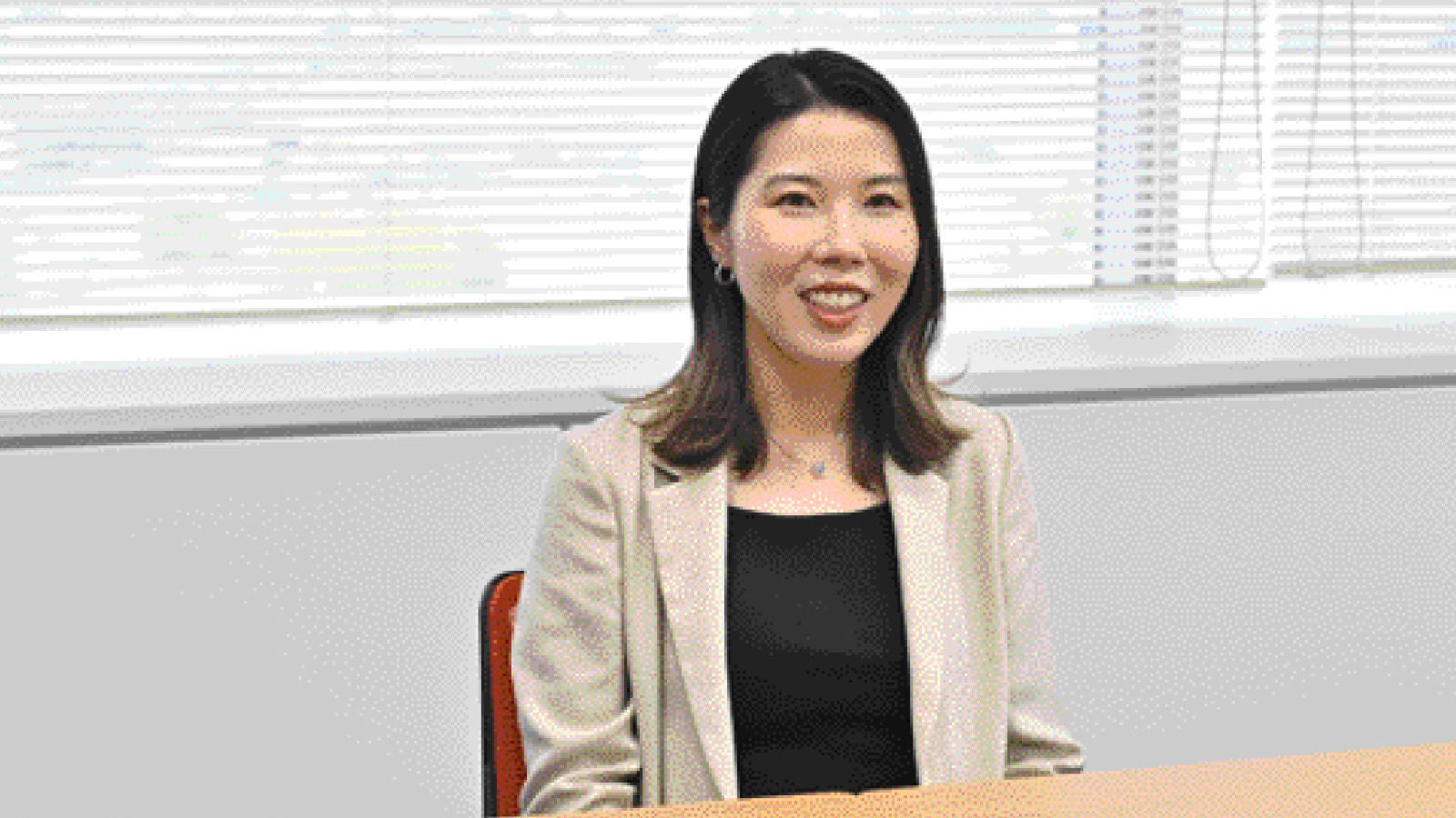 Eine Frau an einem Tisch blickt bei natürlichem Tageslicht aus einem Fenster.