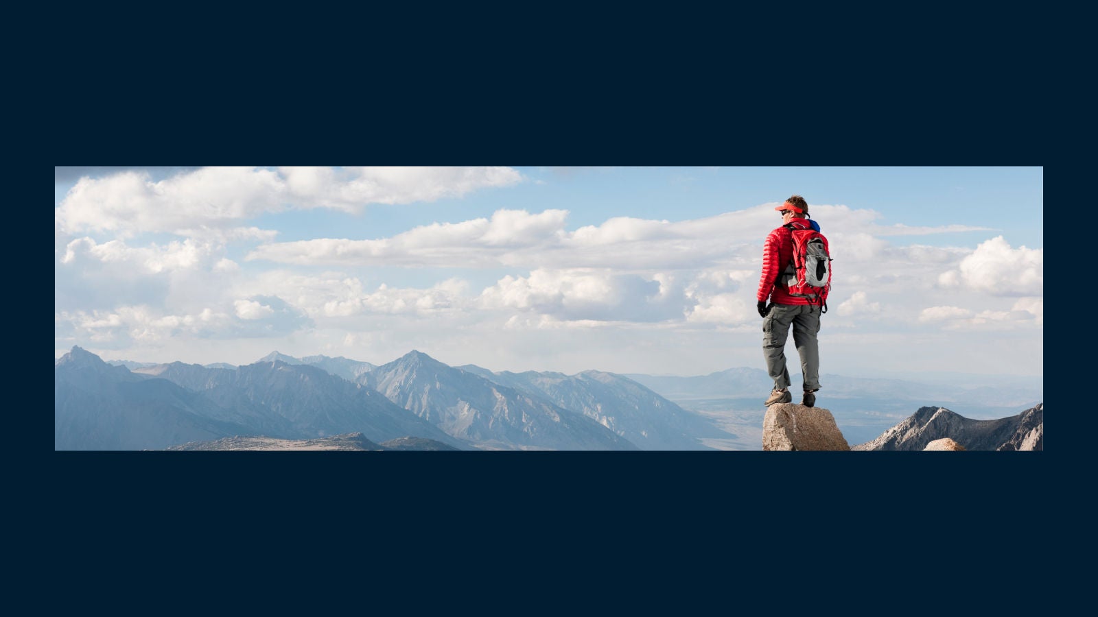 Man with hiking gear standing on top of a mountain