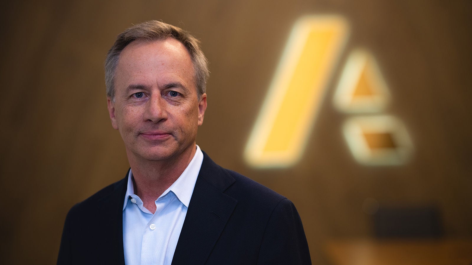 Brian Kober — businessman dressed in suit standing in front of Anaplan logo