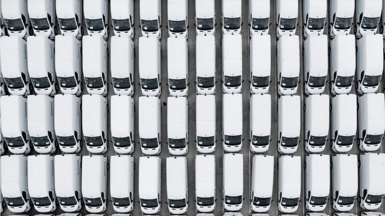 Michelin Customer Story Illustrative Image 2 Overhead view of a large, tightly packed fleet of identical white vans parked in rows in a lot.