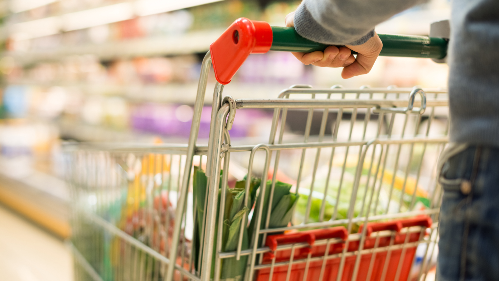 Pietercil Group Customer Story Illustrative Image 1 Close-up of a person pushing a shopping cart filled with groceries in a brightly lit supermarket aisle.